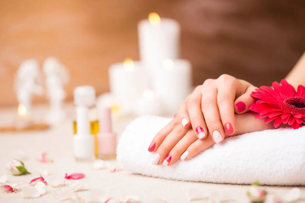 A woman with pink nails is sitting on a towel