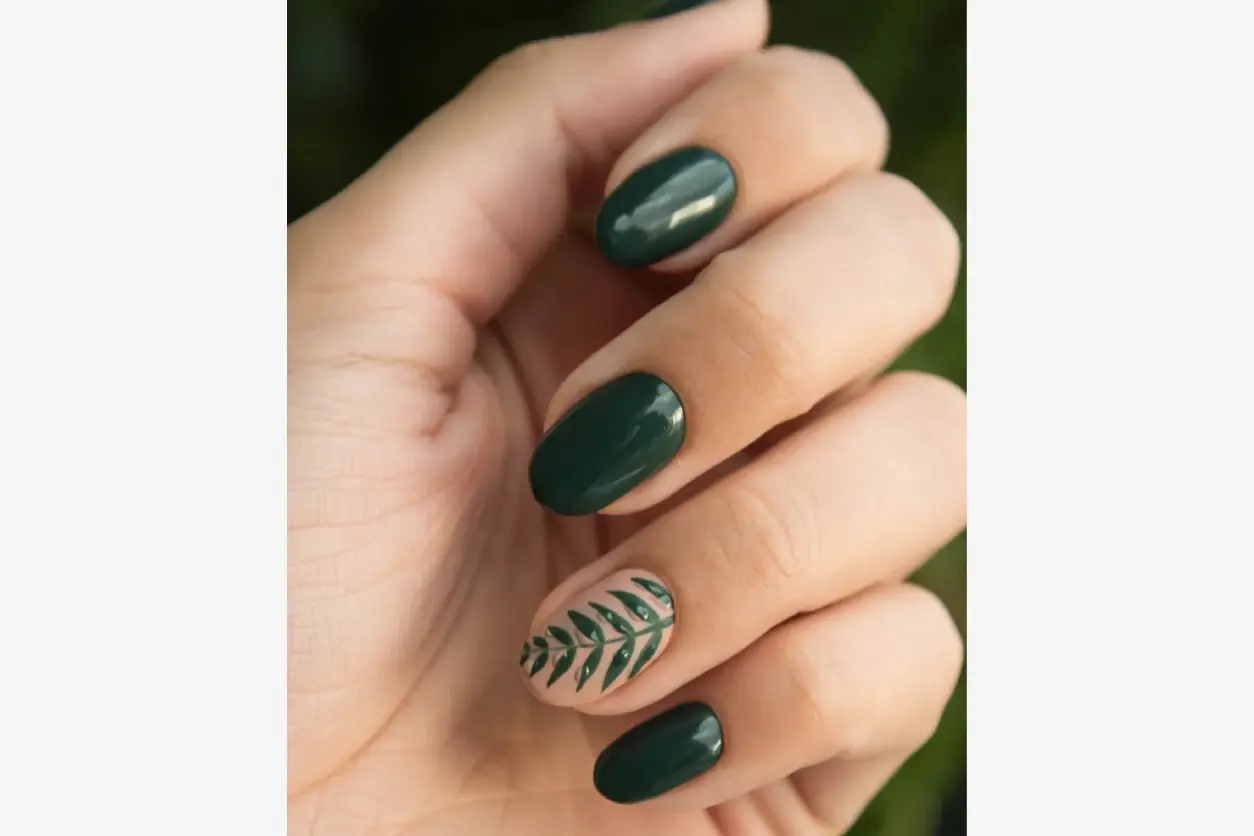 A person with green nails and a leaf design on their finger.
